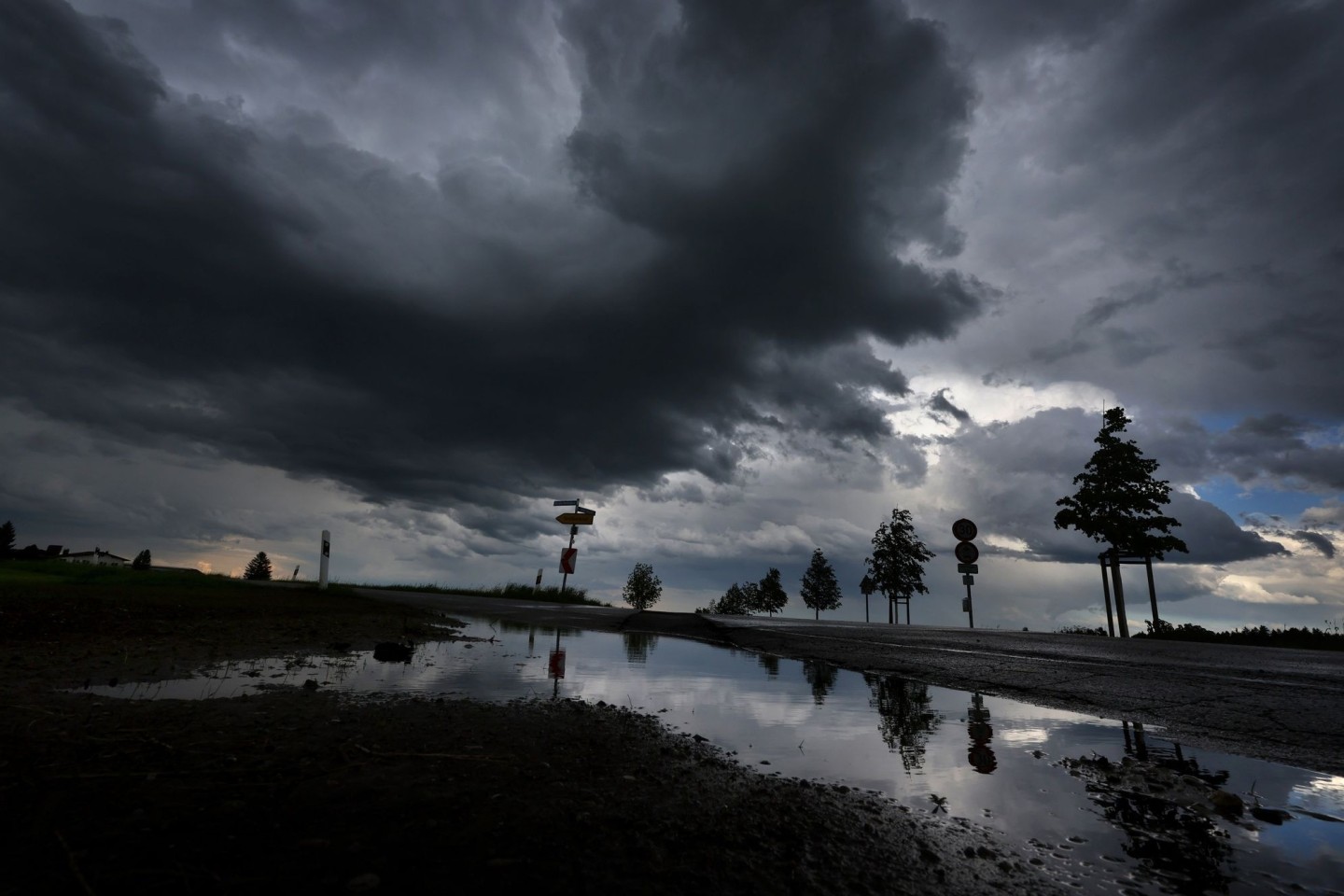 Dichte Regenwolken spiegeln sich in einer Pfütze.