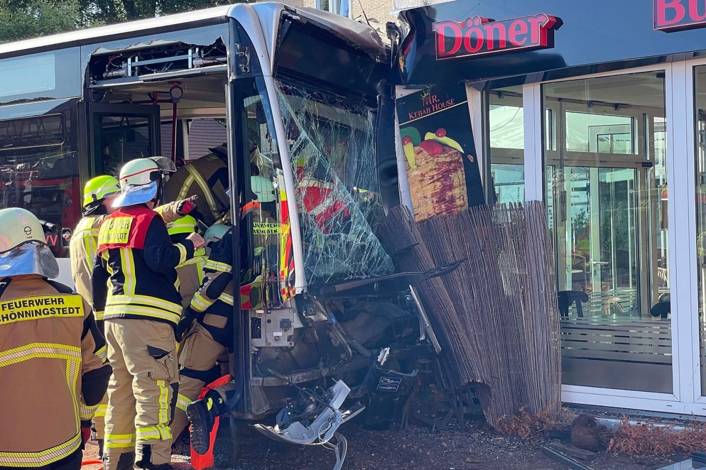 Einsatzkräfte der Feuerwehr untersuchen den Linienbus, der zuvor in einen Dönerladen gekracht war.