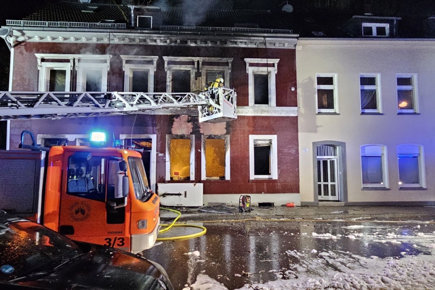 Feuerwehrleute löschen von einer Drehleiter aus ein Mehrfamilienhaus in Essen.